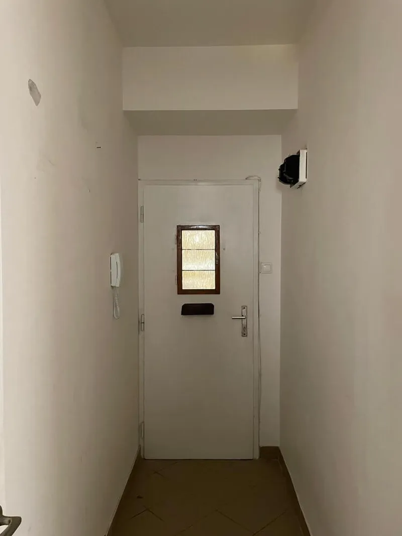 Narrow entry vestibule with white door featuring a frosted glass panel and intercom