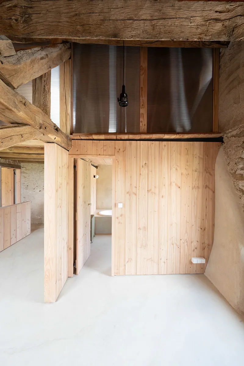 Interior view of vertical timber partition beneath exposed timber beams and corrugated metal mezzanine screen