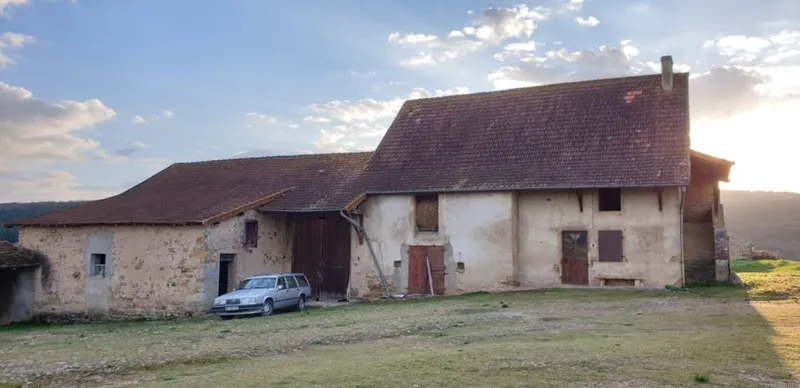 Rendered farmhouse with tiled roof and attached barn under late afternoon sun