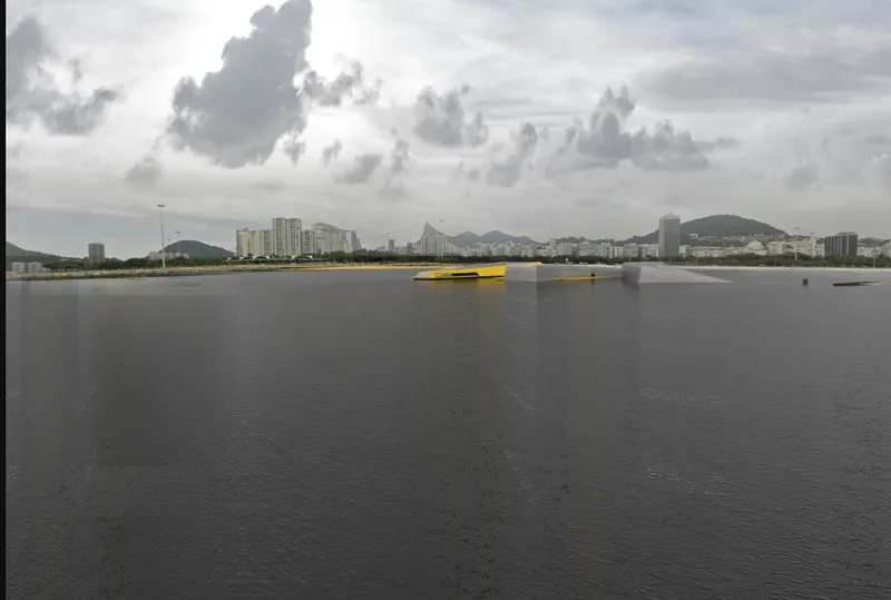 Yellow floating platform on a grey river with mountains and highrise buildings in the distance
