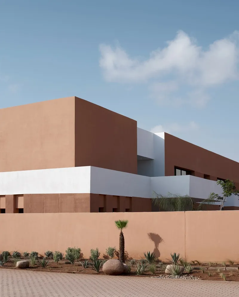 Exterior wall detail showing layered terracotta volumes with planted beds along the perimeter