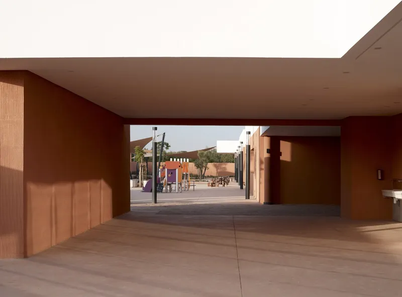 Covered passage with timber-lined wall and deep overhanging ceiling framing a view of the courtyard beyond
