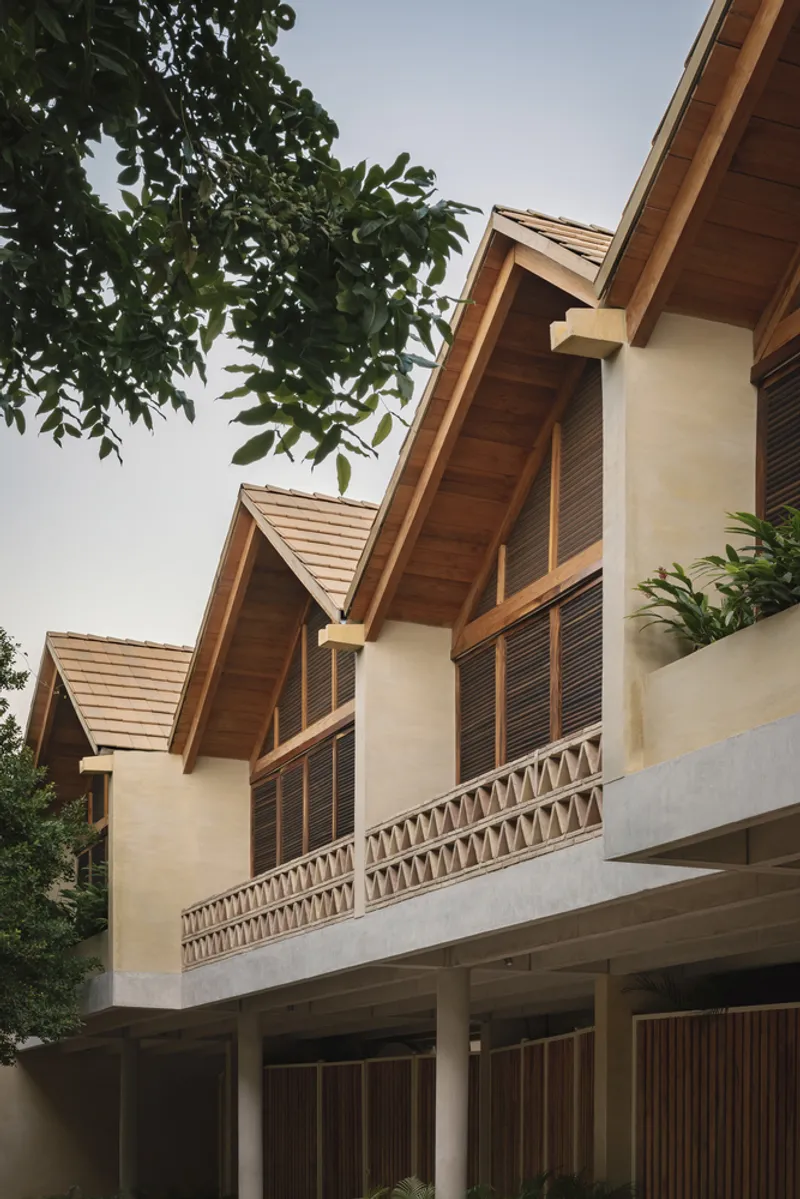 Stepped gable rooflines with exposed timber soffits and louvered shutters beneath overhanging tree branches