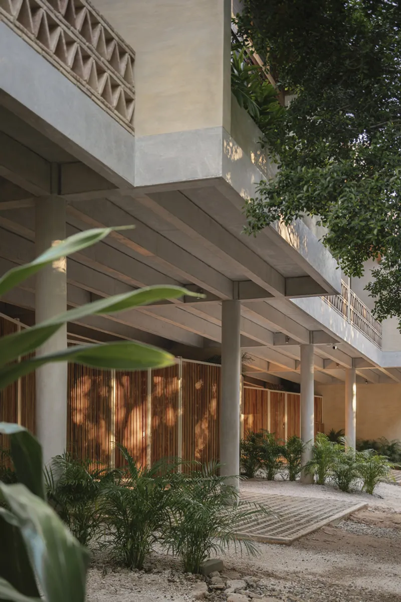 Covered entry colonnade with exposed timber beams and vertical wood screens lit by warm afternoon light