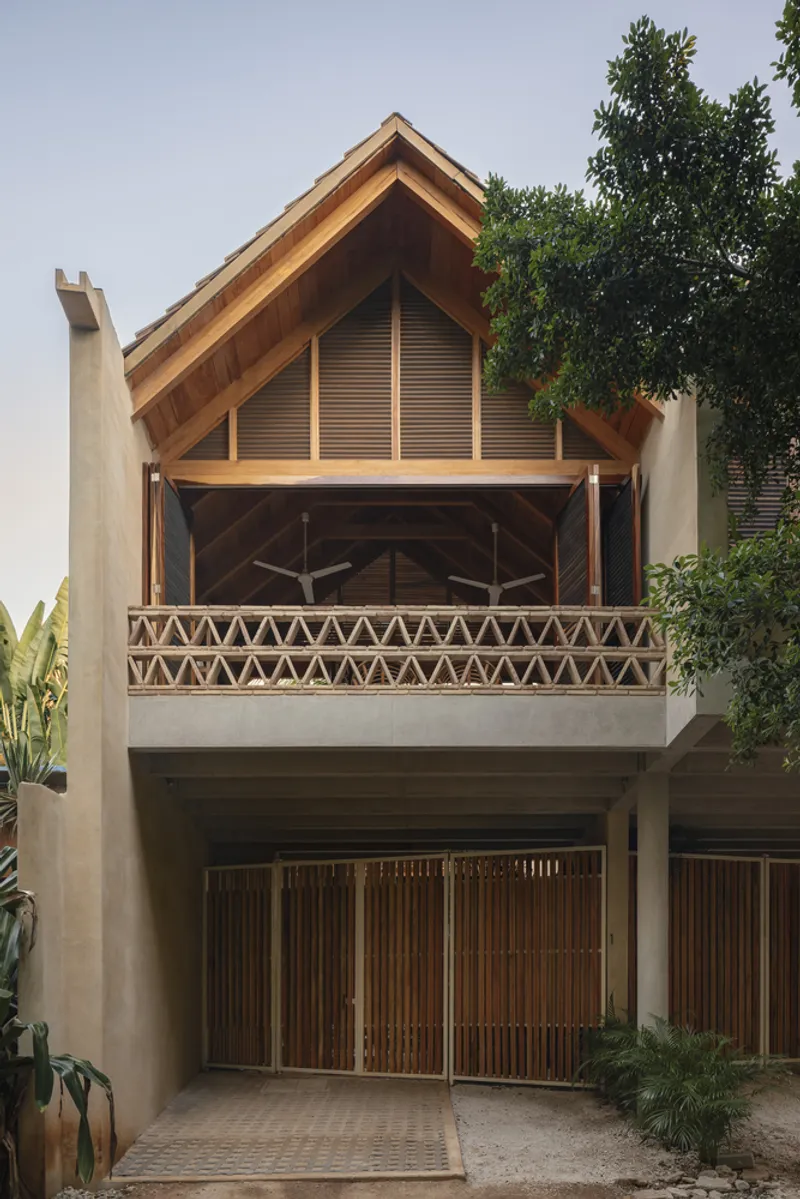 Street facade showing gabled timber roof with triangular balustrade and vertical slat shutters between palm fronds