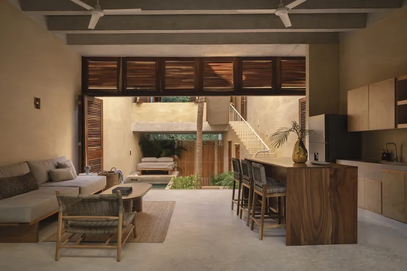 Open-plan living space with walnut kitchen island and slatted timber doors framing courtyard view