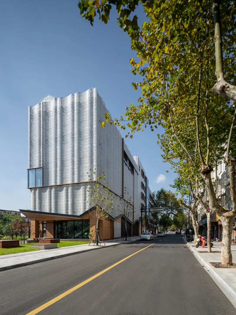 Cantilevered upper floors clad in corrugated metal panels hovering over a timber and glass ground level