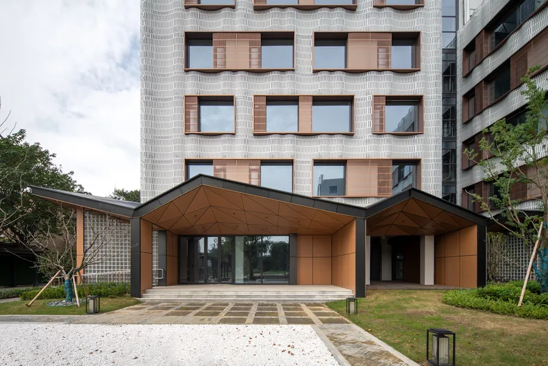 Ground level view of the dual copper canopies sheltering the entrance with patterned paving and young trees