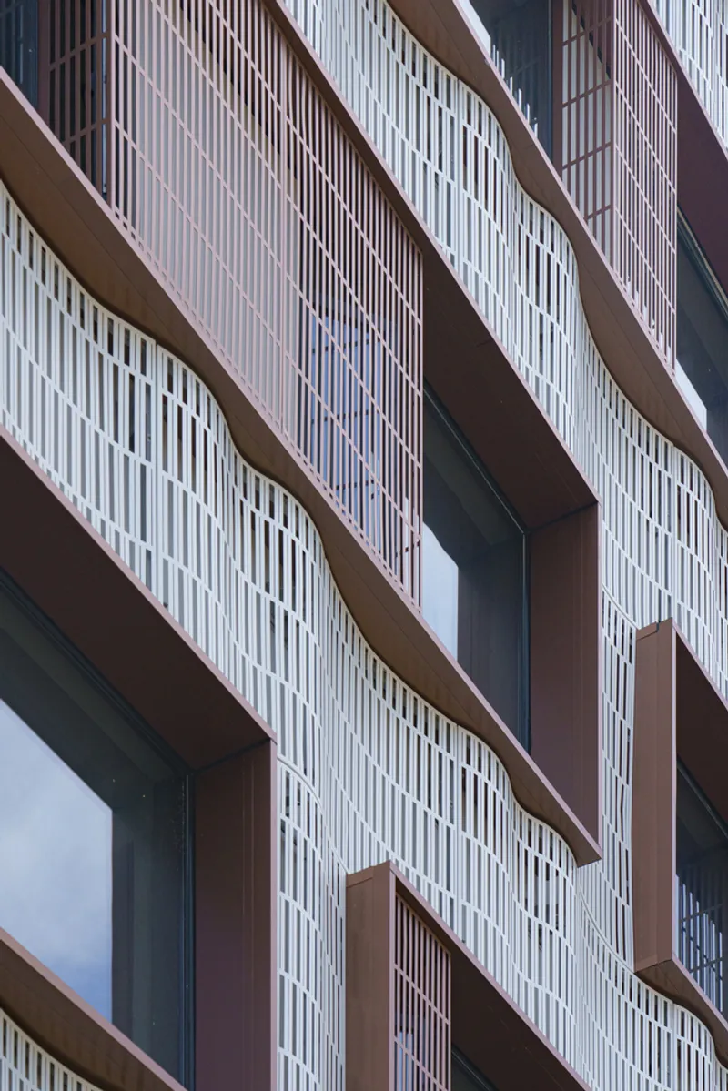 Close-up of the staggered balconies with vertical white screening and bronze-toned soffits
