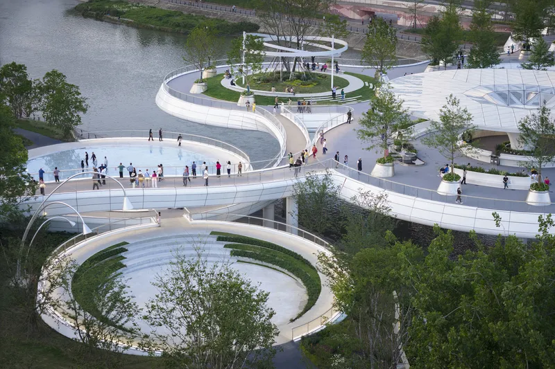 Aerial view of the spiraling white pathways encircling planted lawns and trees along the waterfront