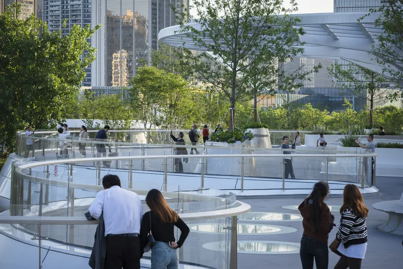White circular terraces with glass railings and visitors overlooking a reflective pool surface