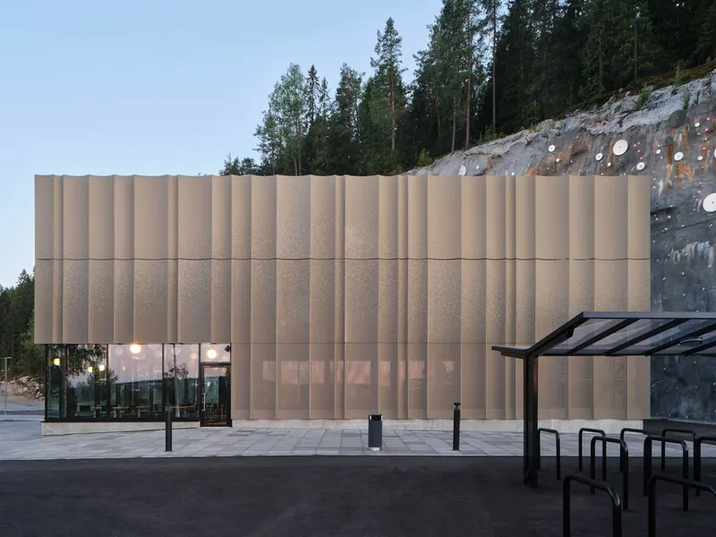 Close-up of the vertical ribbed facade panels beside the excavated rock face at twilight