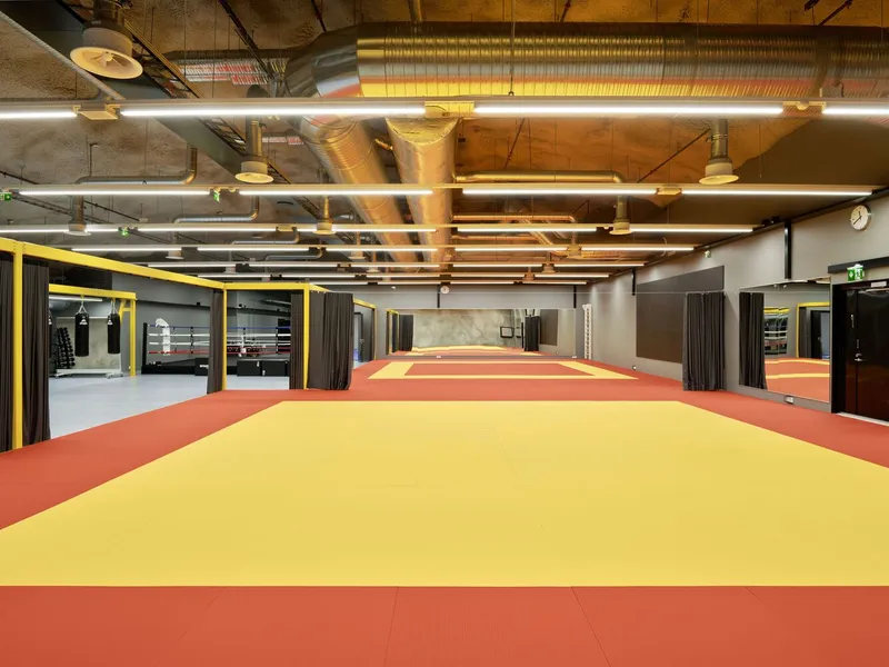 Training room with yellow and red mat flooring under exposed timber ceiling and linear lighting