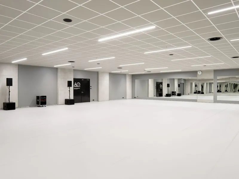 White dance studio with full-height mirrors along one wall and acoustic tile ceiling grid
