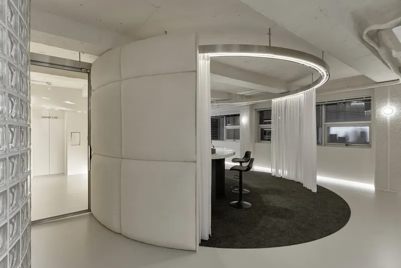 Curved corridor with circular curtain enclosure and glass block wall at left