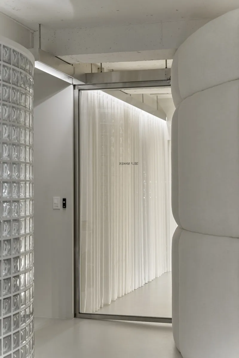 Glass block wall beside a framed doorway with backlit pleated curtain screen
