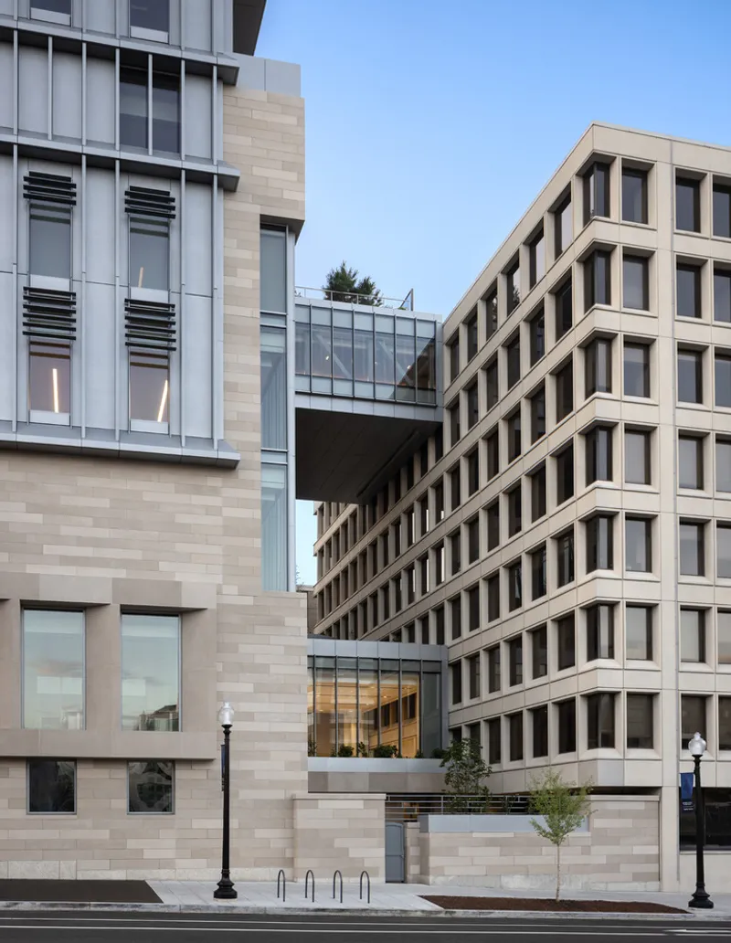 Glazed skybridge connecting two volumes with limestone cladding and punched windows