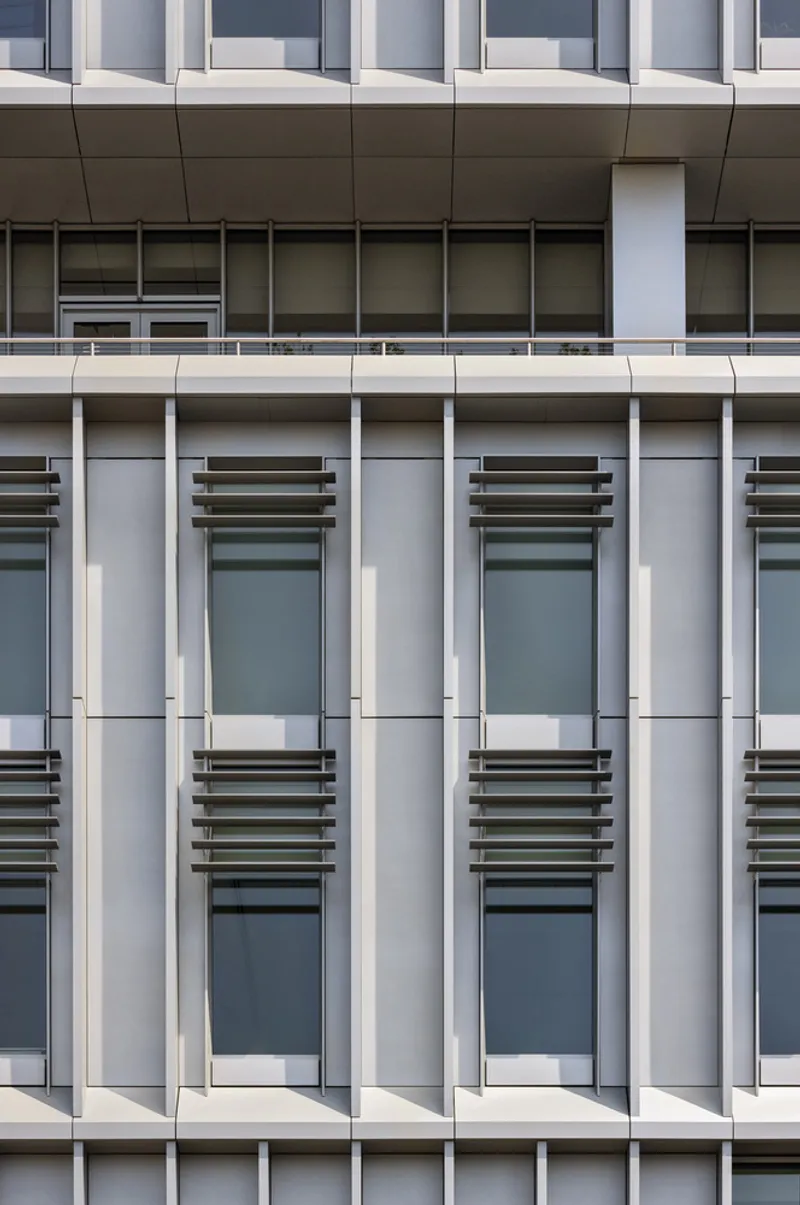 Facade detail showing vertical white fins alternating with recessed windows across multiple floors