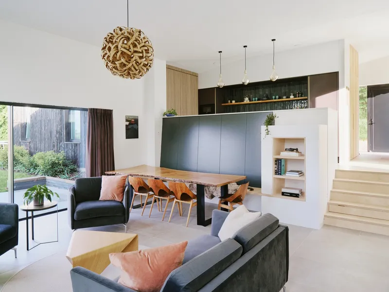 Open living and dining space with live-edge table, pendant lights and built-in cabinetry under stairs