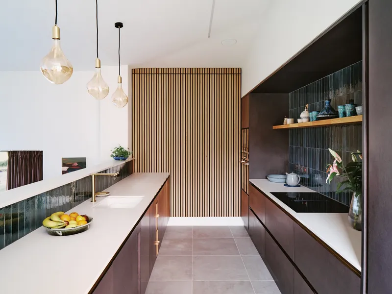 Kitchen with vertical timber slat screen dividing the space and green backsplash tiles