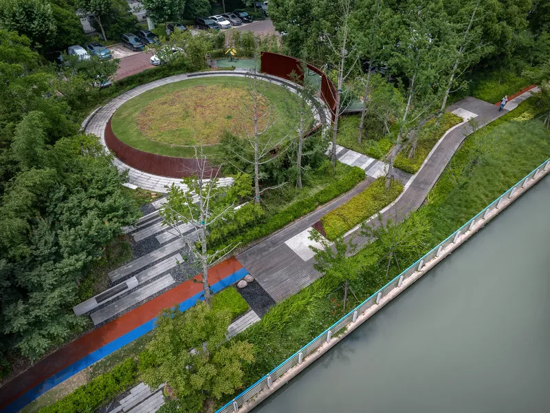 Overhead view of the circular lawn amphitheater ringed by weathering steel retaining walls and young birch trees