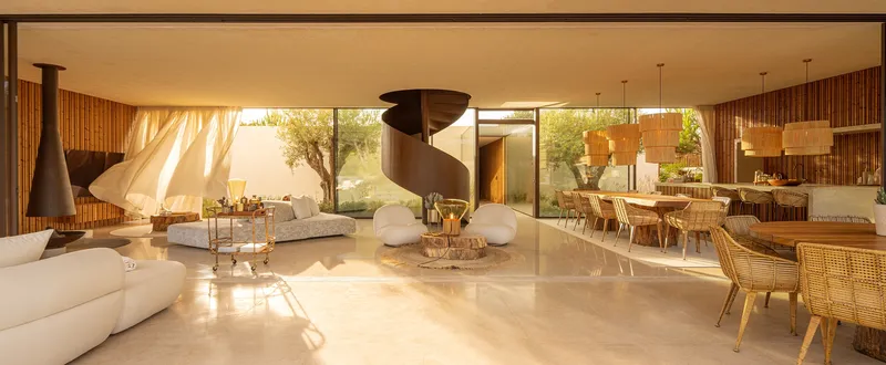 Open-plan living and dining space with steel spiral staircase in afternoon light