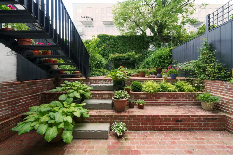 Stepped brick terraces with stone treads and hostas leading through planted courtyard garden
