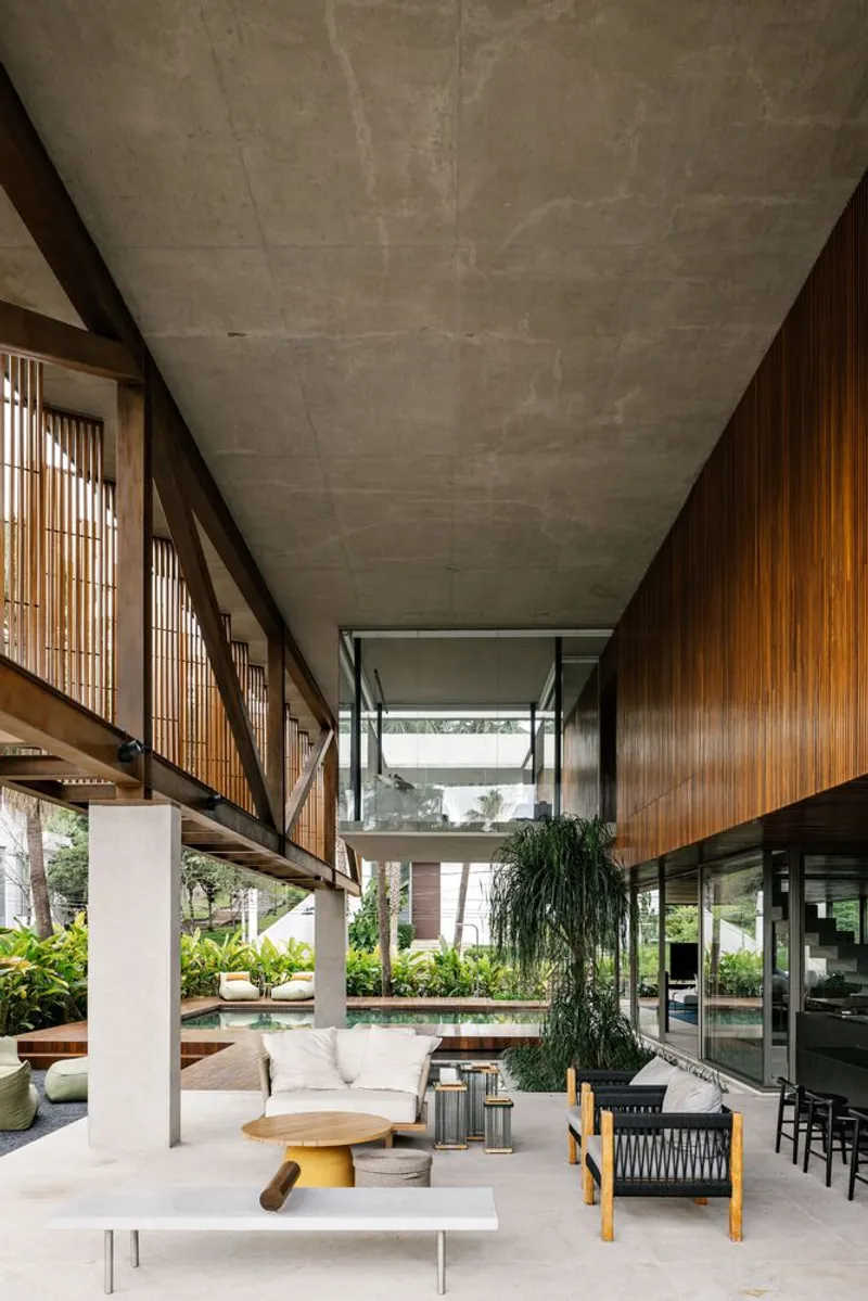 Open living area with exposed concrete ceiling beams and timber screen walls overlooking the garden