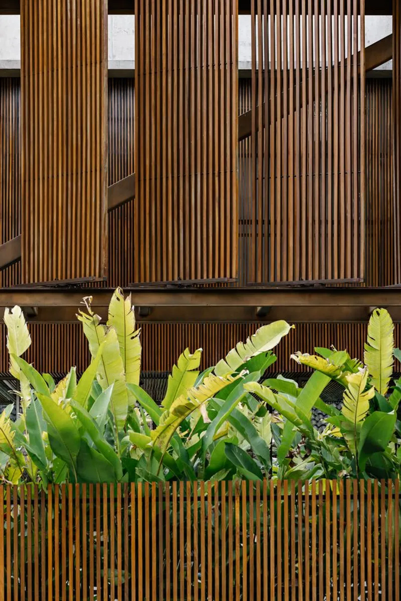 Vertical timber slat screen with integrated planter boxes filled with banana palms