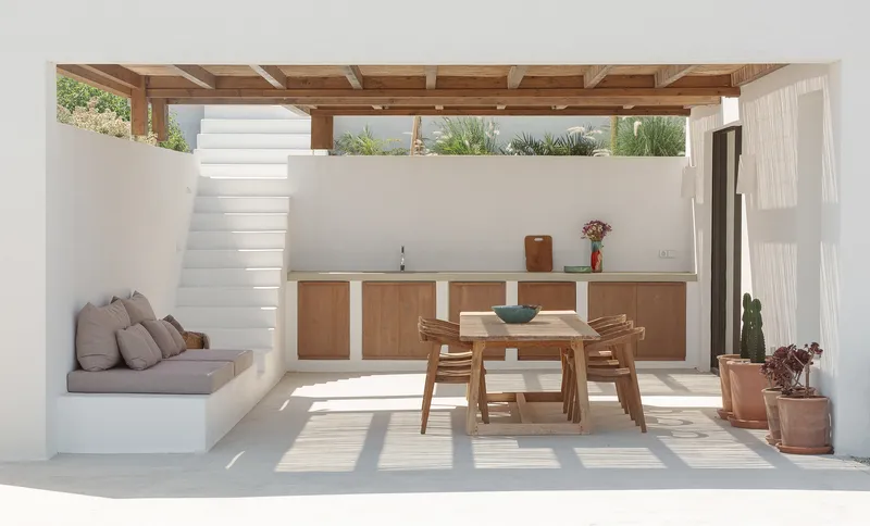 Covered outdoor terrace with timber pergola, built-in bench seating and staircase to rooftop garden