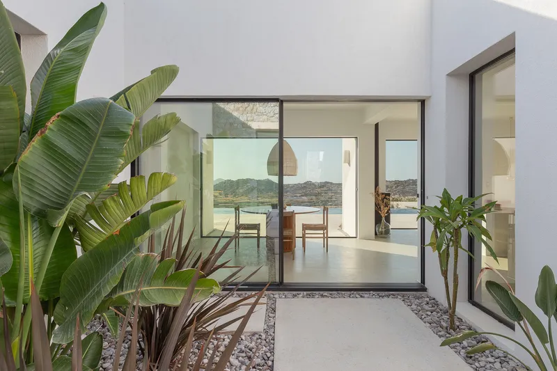 Glass doors opening from dining area to terrace with planted gravel beds and banana palms