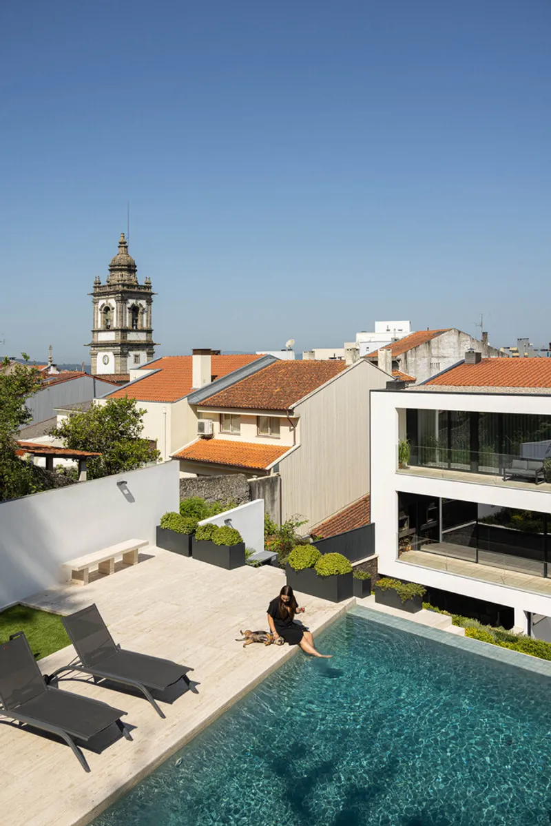 Rooftop terrace with a pool and distant church bell tower under blue sky