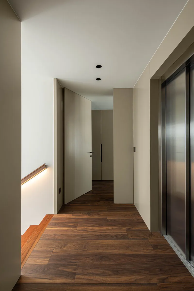 Corridor with dark timber flooring, recessed lighting, and a steel elevator door beside flush panel doors