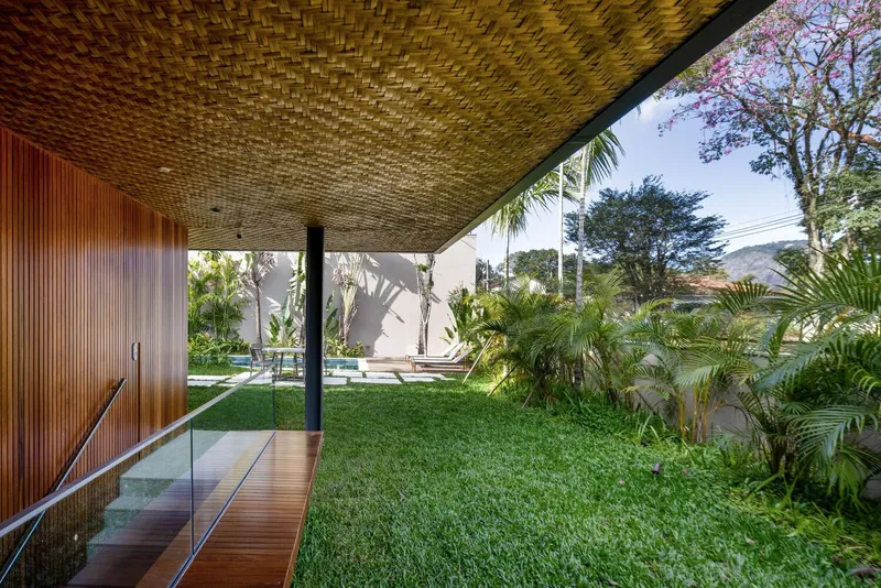 View beneath the woven ceiling canopy toward a grassed courtyard with pool and palm plantings