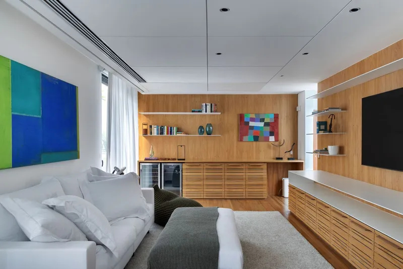 Media room with timber cabinetry and white sofa beneath recessed ceiling panels