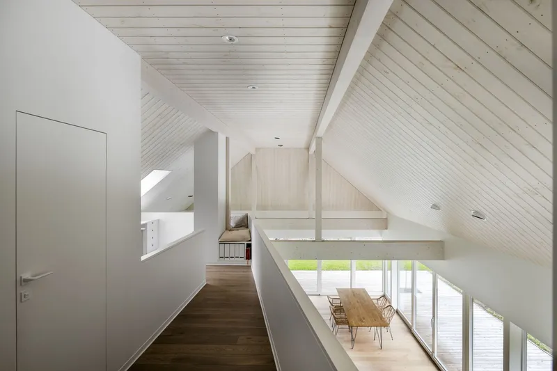 Upper level hallway with glass balustrade overlooking the dining area below and sloped timber ceiling