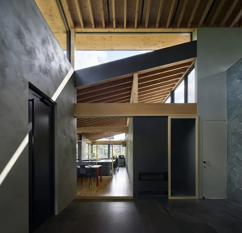 Entry hall with polished concrete floor, concrete walls and timber-framed mezzanine bridge under exposed wood ceiling