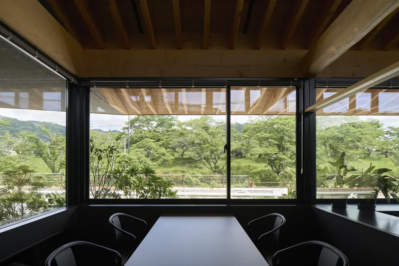 Corner dining nook with black-framed windows, timber beam ceiling and views to rolling green hills