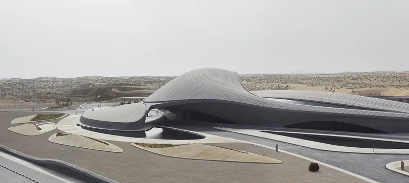 Side view showing the curved shell structure rising from the arid landscape under overcast skies