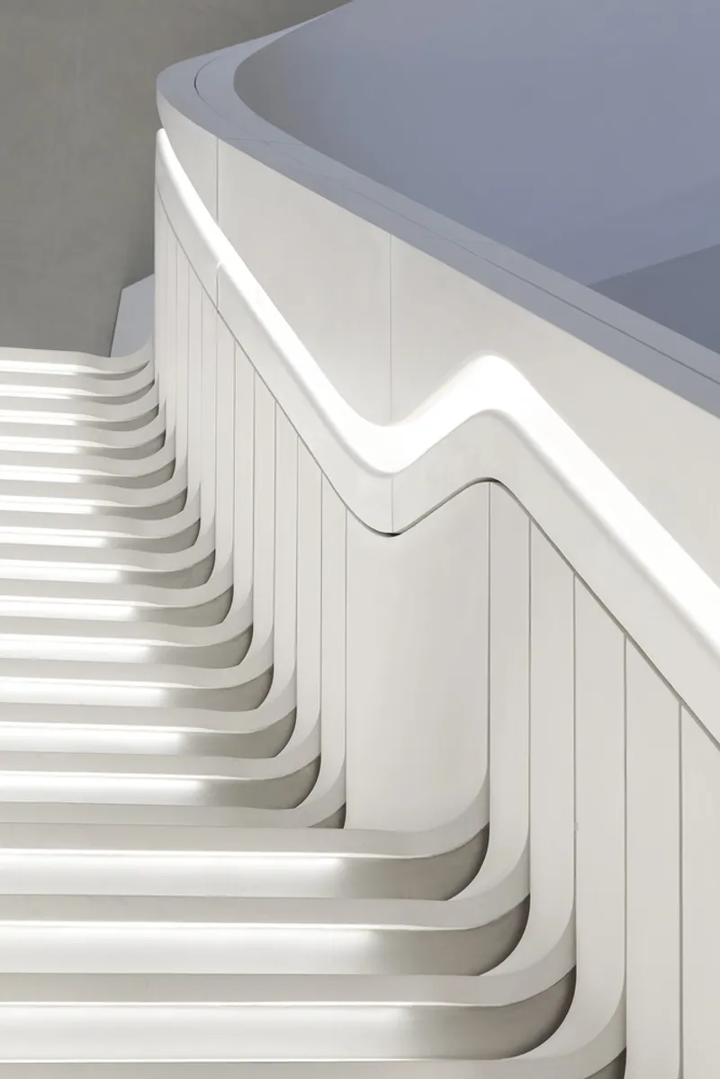 Close-up of illuminated stair treads with curved handrail and paneled wall detail