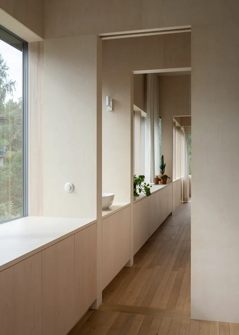 Bathroom corridor with built-in timber cabinetry and freestanding tub lit by recessed skylights
