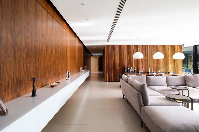 Open plan living space with walnut paneling, white kitchen counter and three pendant lights over dining area