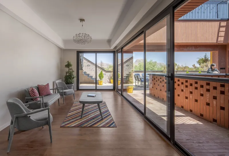 Interior living room opening through sliding glass doors to a terrace with chequered brick screening under bright daylight
