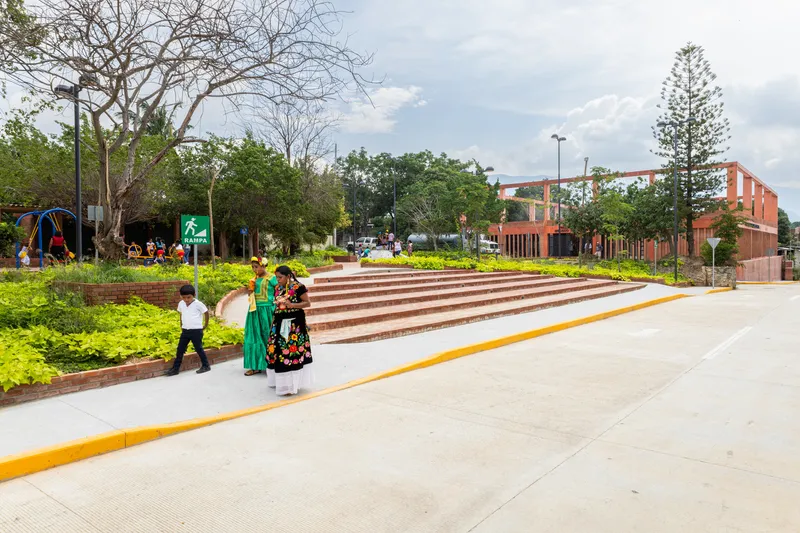 Stepped brick amphitheater with yellow striped concrete ramp as visitors in traditional dress pass by