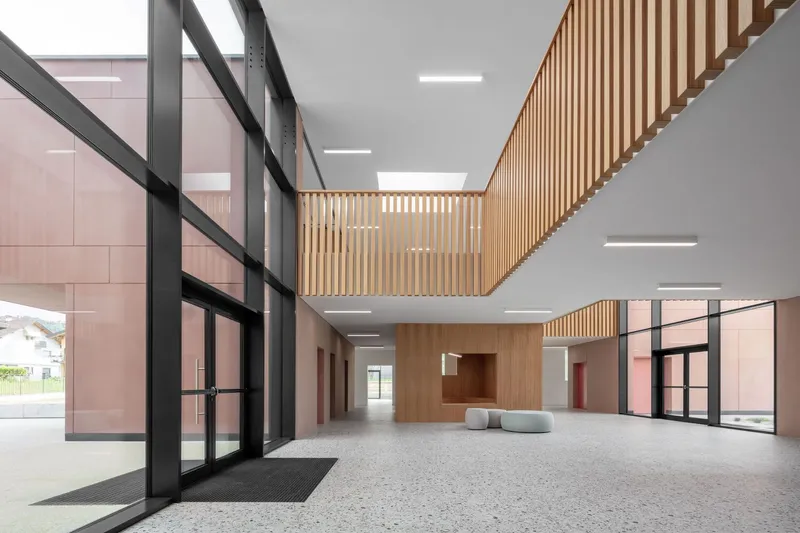 Double-height lobby with timber slatted ceiling and terrazzo flooring below recessed linear lighting