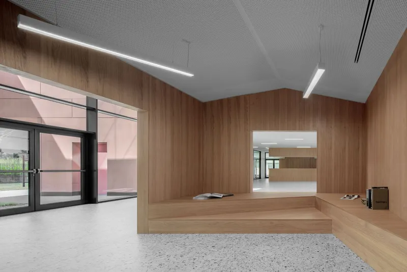 Interior foyer with timber-clad platform and walls, terrazzo flooring and perforated acoustic ceiling panels