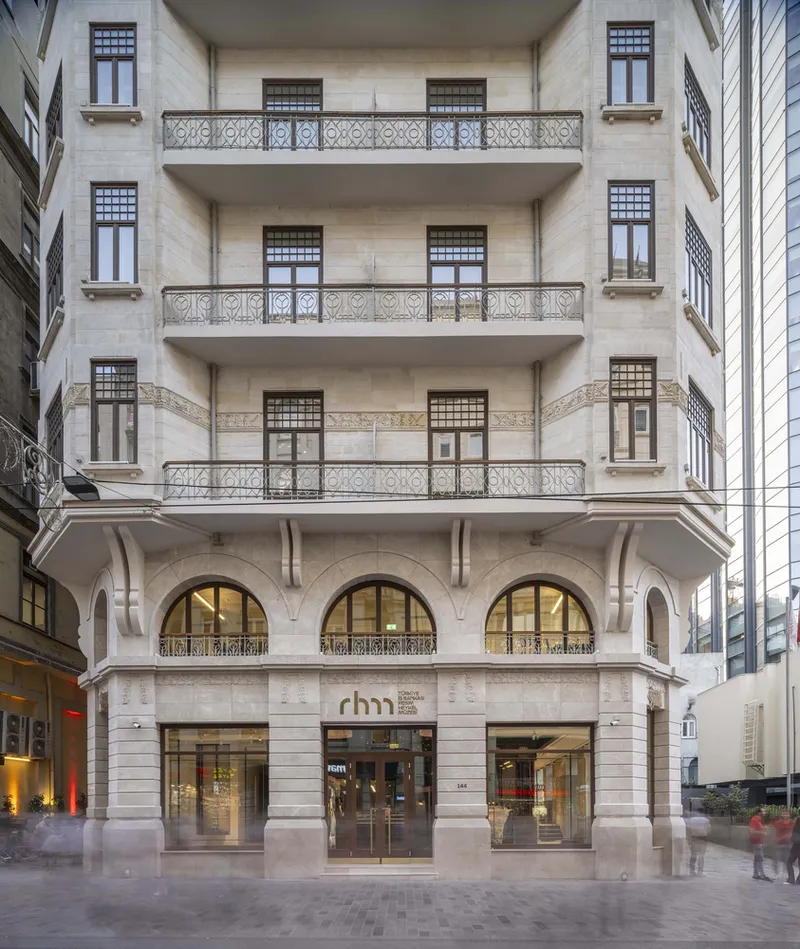 Facade with limestone arched colonnade, ornamental balconies and patterned windows at twilight