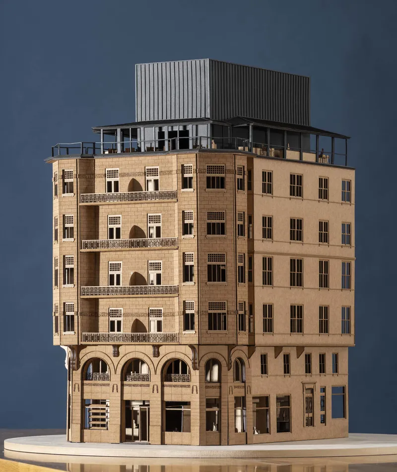 Sectional architectural model of a multi-storey stone building with glass-topped addition under dramatic lighting