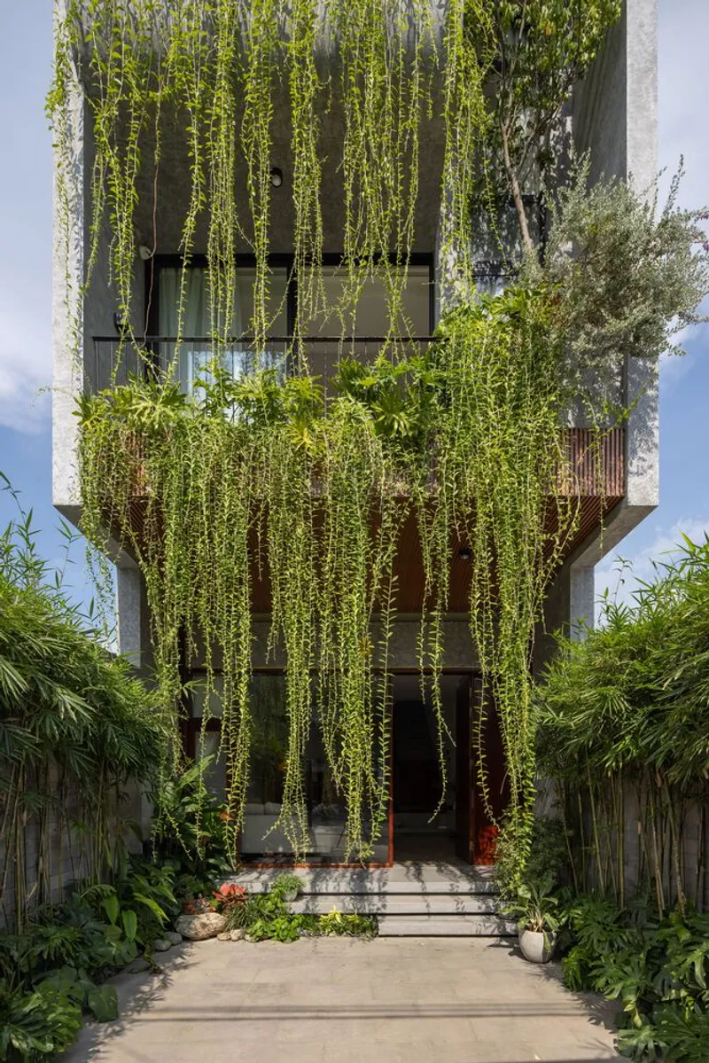 Street facade with cascading vines draping from timber slat screens and balconies under blue sky