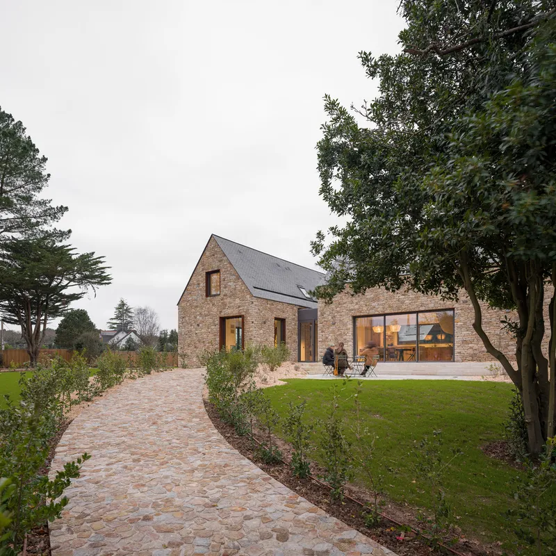 Cobbled stone pathway leading to the glazed elevation with a person seated on the terrace